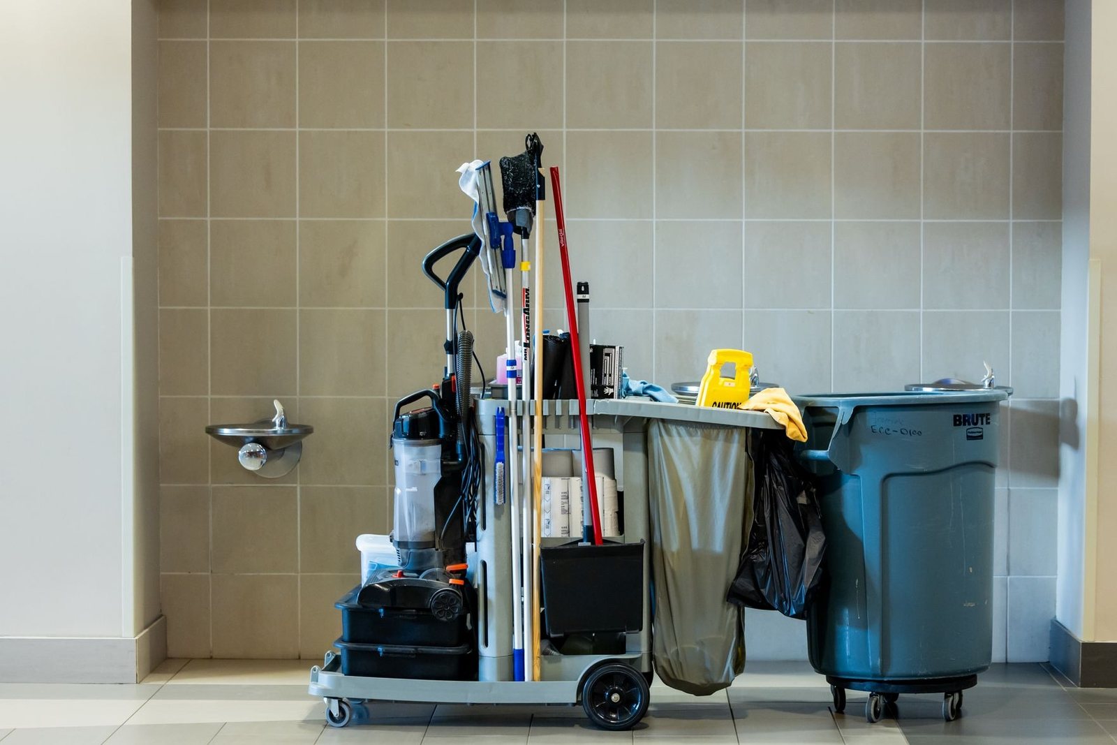 Janitorial cart stocked with supplies in a tiled washroom